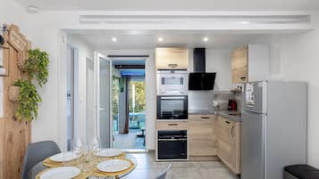 Une cuisine compacte dotée d’appareils électroménagers modernes, un coin repas avec une table en verre et une vue sur l’extérieur.