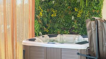 A hot tub with a wall of greenery behind it.