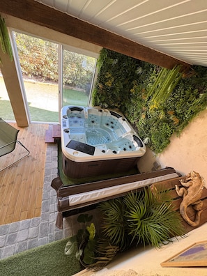 Un bain à remous situé dans un espace extérieur abrité, avec vue sur un jardin et doté de mobilier de patio.