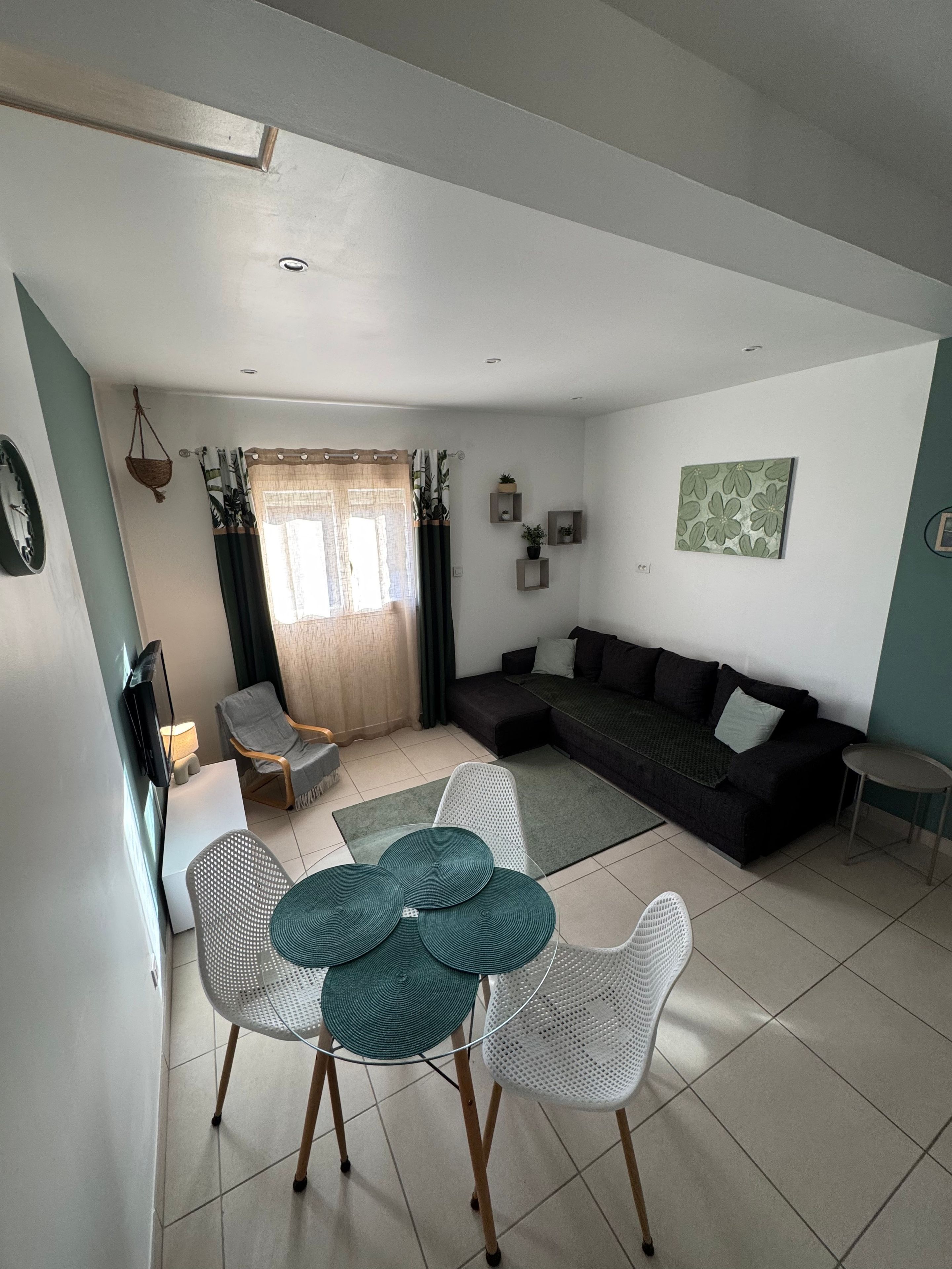 A living room with a dark-colored sofa, a white coffee table, and a dining area with a round table and chairs.