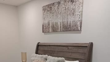 Ett sovrum med en säng, ett sängbord, en lampa, ett runt bord och ett konstverk som hänger på väggen.