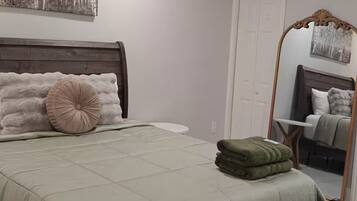 A bedroom with a bed, a ceiling fan, a large mirror, and a door.