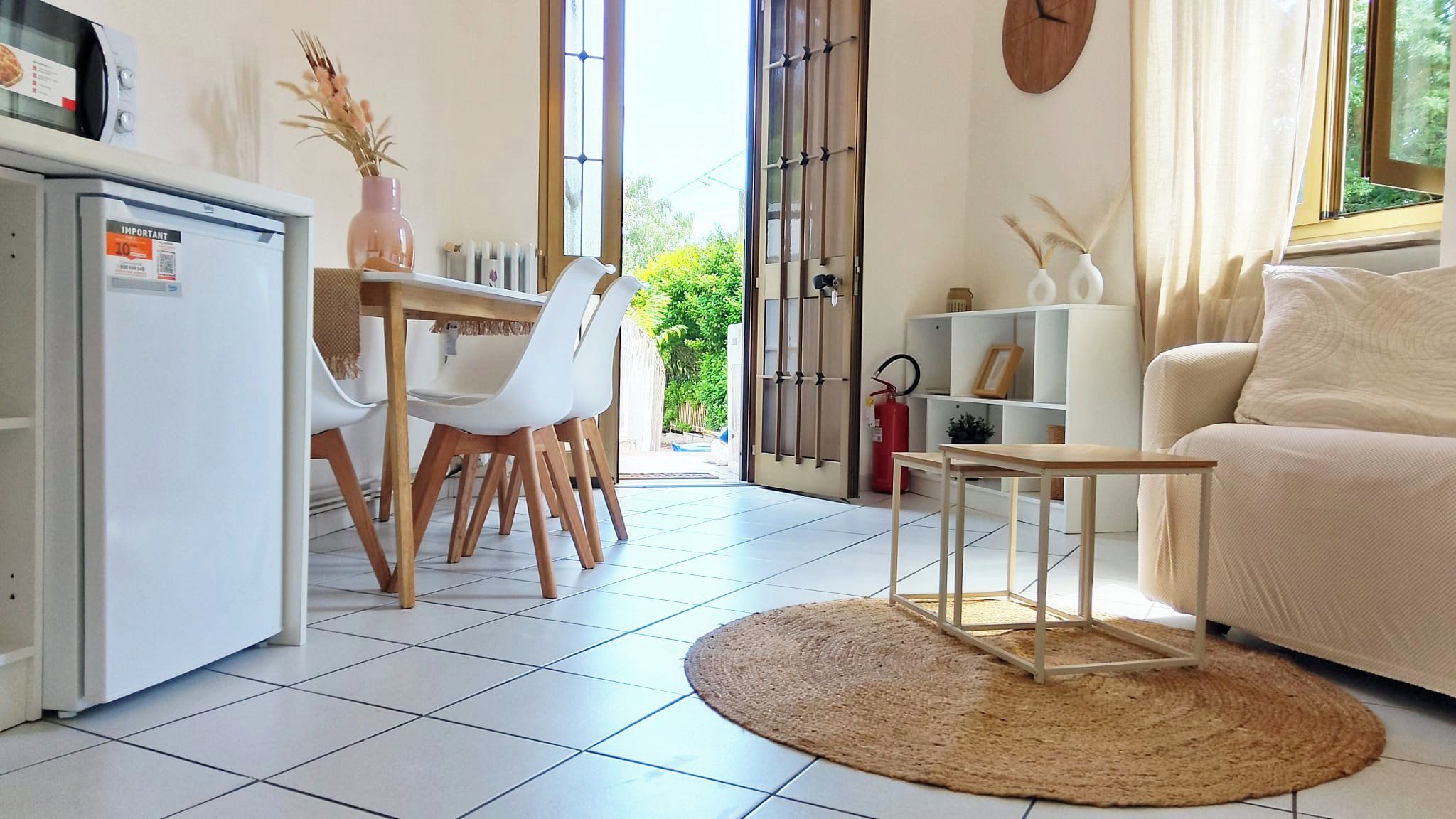 Un salon moderne comprenant un canapé, un coin repas avec des chaises et une table, ainsi qu’une cuisine équipée d’un réfrigérateur.