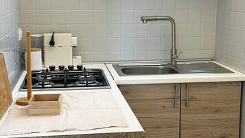 A kitchen with a gas stove, a sink, and wooden cabinets.