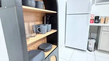 Una cocina compacta con almacenamiento integrado, un refrigerador y una cafetera.