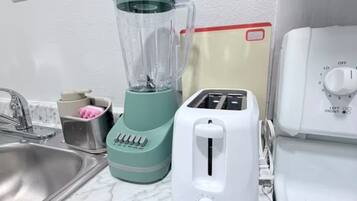 A kitchen with a blender, toaster, and a white stove.