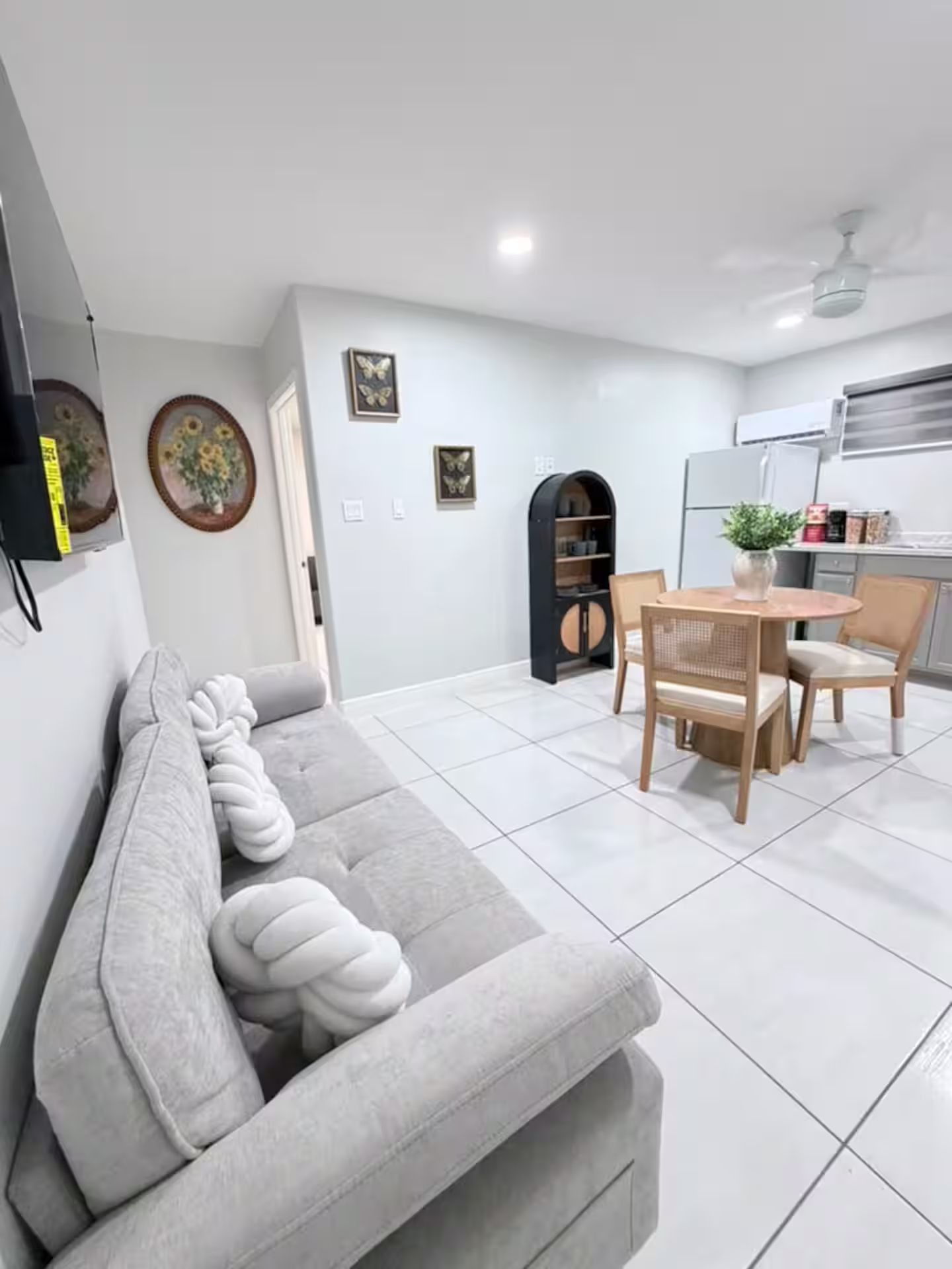 A modern living room with a sofa, dining table, chairs, and a kitchen area.