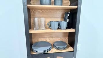 A dark-colored, arched display cabinet with multiple shelves, containing various items like cups, glasses, and plates.