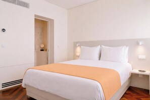 Une chambre d’hôtel avec un lit, une table de chevet et une porte donnant sur une autre pièce.