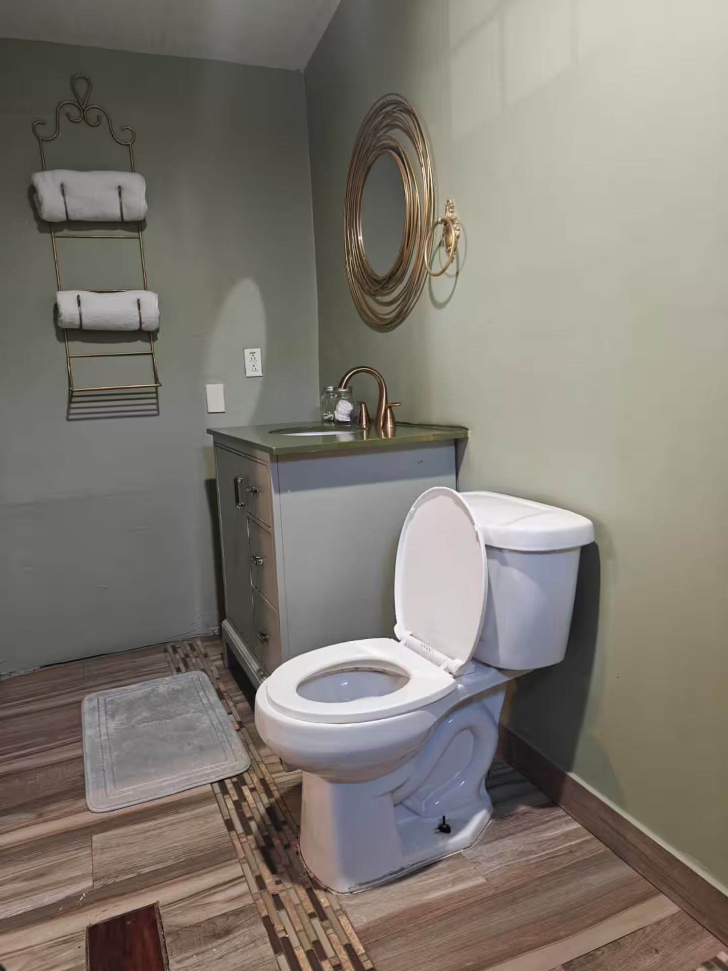 Et badeværelse med toilet, håndvask og et dekorativt spejl.