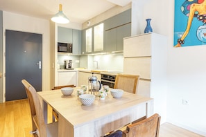A compact kitchen with a dining table, chairs, and a coffee maker. - Le B3 de Claire (Mont-Dore)