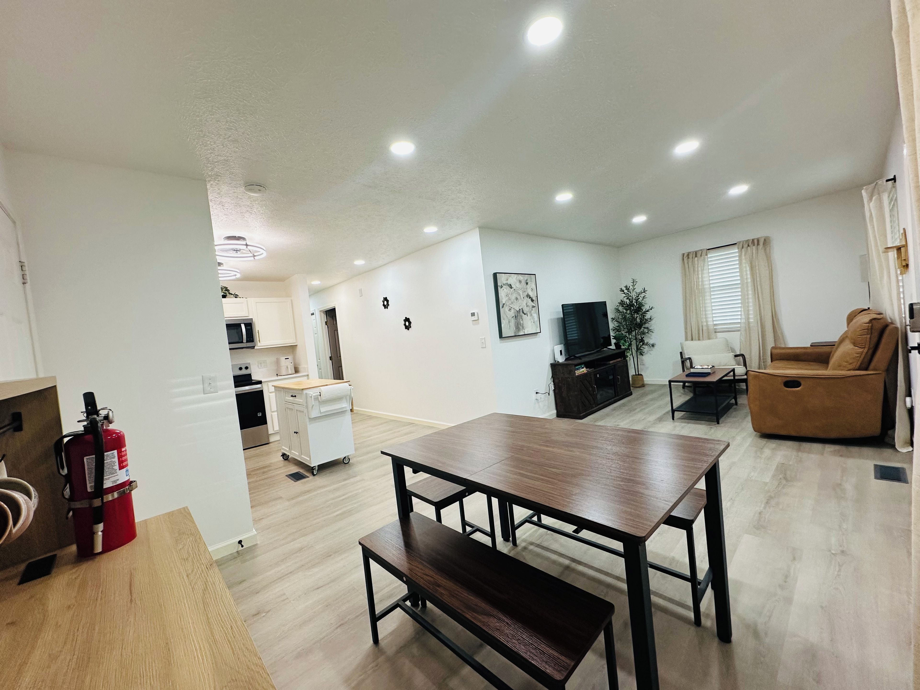 A modern apartment with a dining area, kitchen, living room, and a balcony.