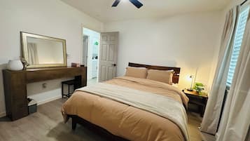 Ein Schlafzimmer mit Bett, Nachttisch, Lampe und Deckenventilator.