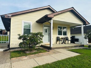 A single-story house with a porch, a small garden, and a visible number '21' on the door.
