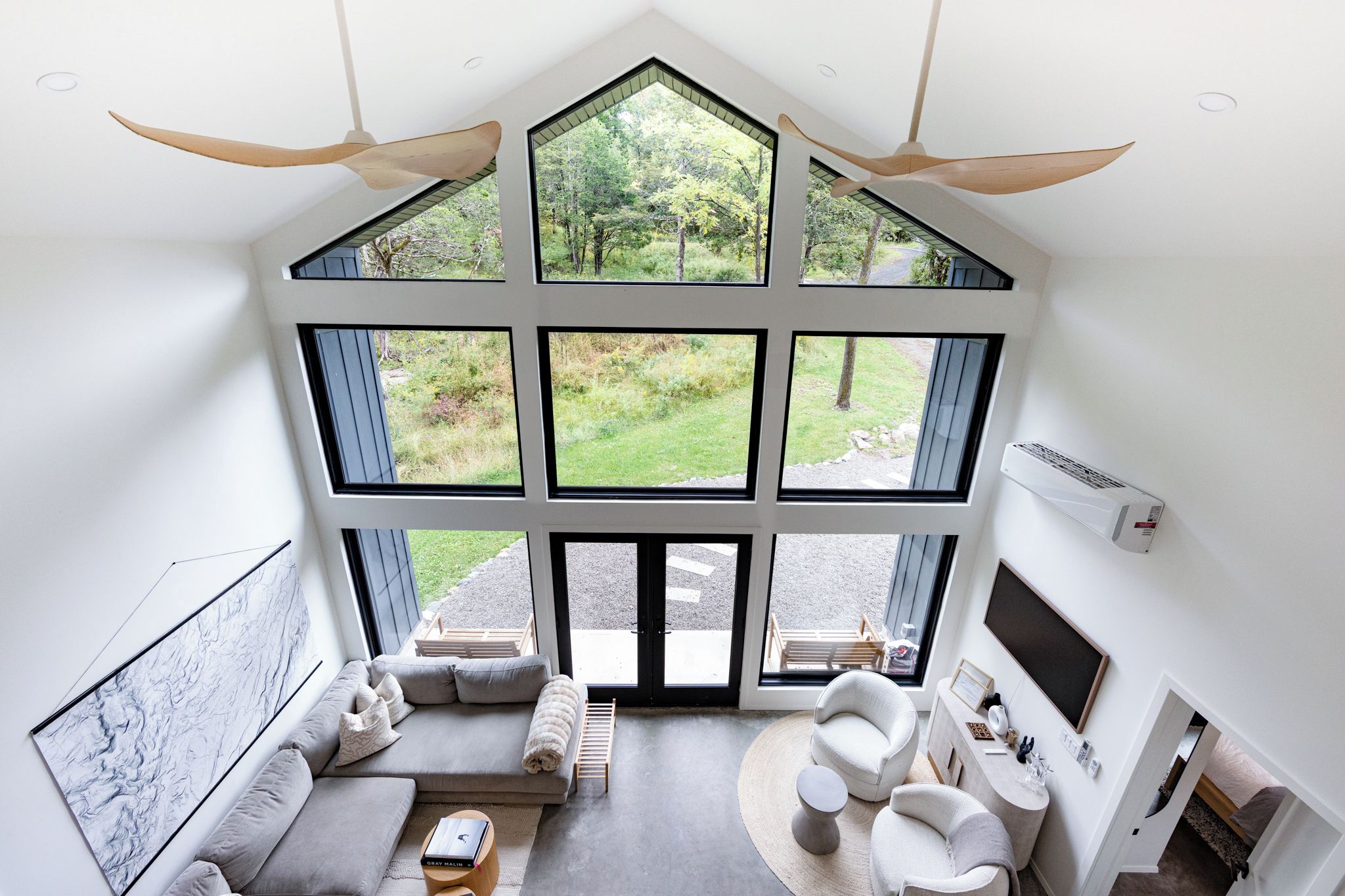 A modern interior with a large skylight, a sofa, a chair, and a fireplace.