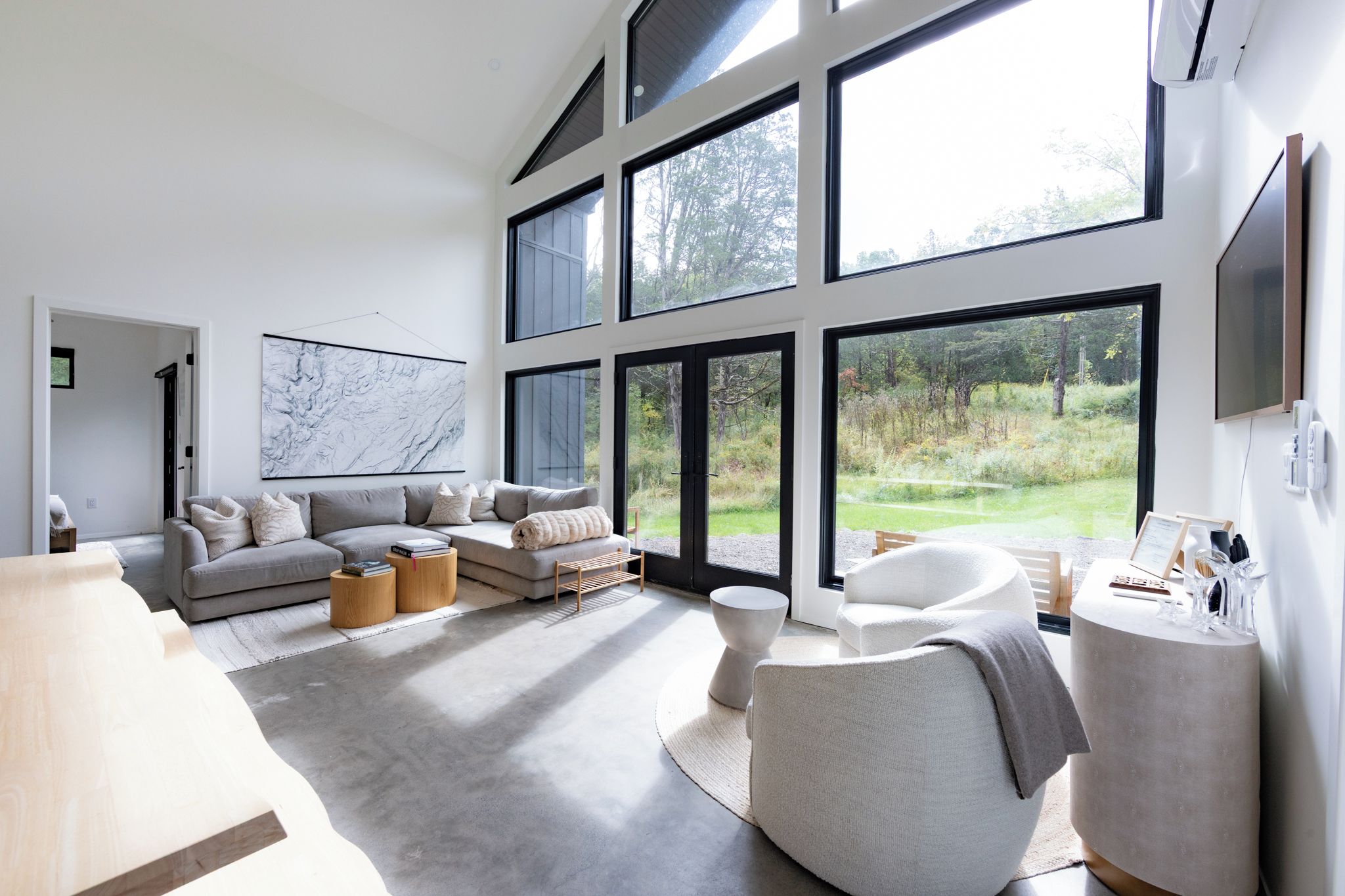 A spacious living room with a large window, a gray sofa, and a round coffee table.