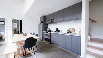 A modern kitchen with grey cabinets, a wooden dining table, and black chairs.