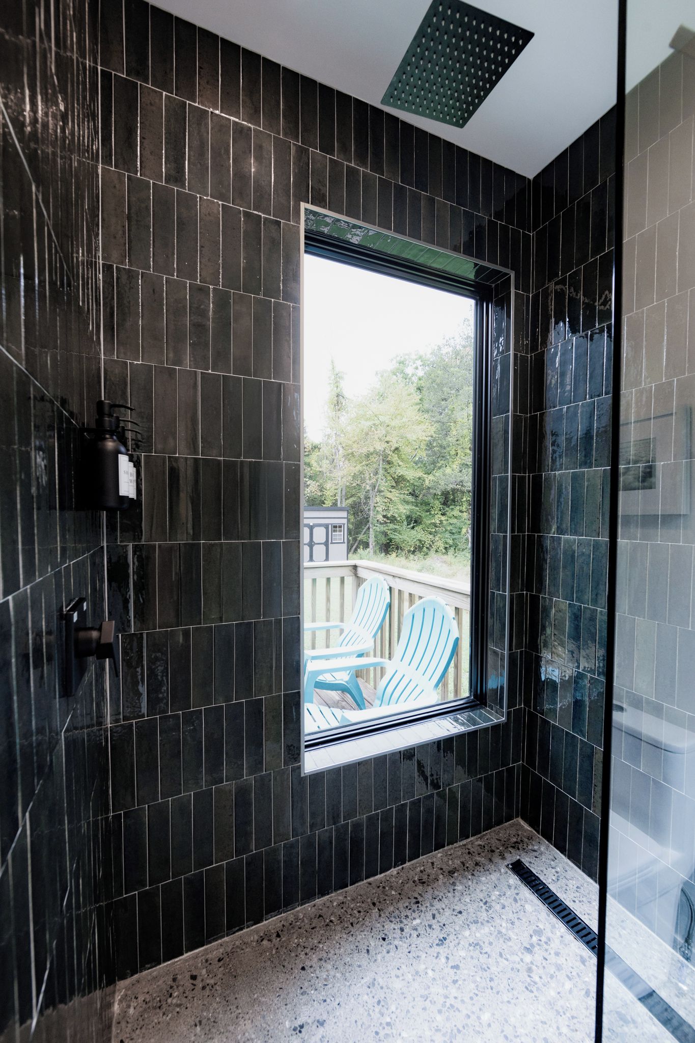 A modern bathroom with dark tiles, a window, and a shower area.