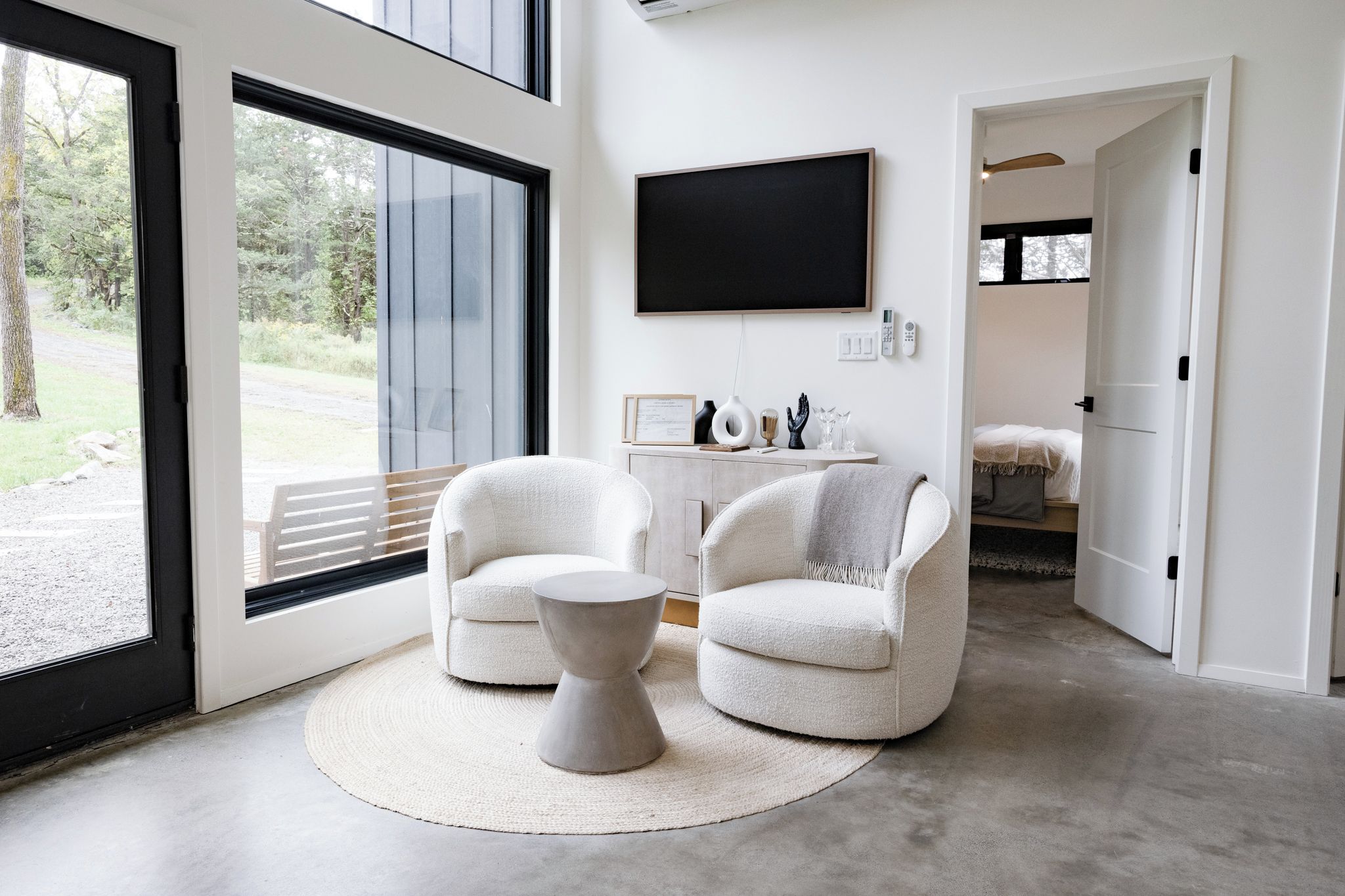 A modern living room with two armchairs, a coffee table, and a flat-screen TV mounted on the wall.