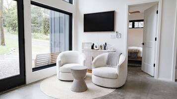 A modern living room with two armchairs, a coffee table, and a flat-screen TV mounted on the wall.