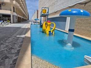 A swimming pool with a slide and a water play area, surrounded by lounge chairs and a building with a stone facade. - Hurghada Lavanda Beach Resort (Hurghada)