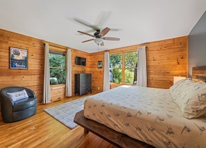 A bedroom with a bed, a ceiling fan, a dresser, a television, and large windows. - Rocky Top Retreat-Hot Tub, Game Room, Garage, View (Maggie Valley)