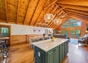 A spacious kitchen with a large island, wooden ceiling beams, and a dining area with a table and chairs. - ROCKY TOP RETREAT - Perfect for Skiers and Holiday Travelers (Maggie Valley)