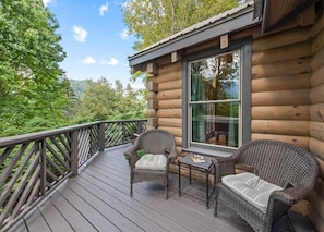 A log cabin with a deck featuring wicker furniture and a glass door. - Rocky Top Retreat-Hot Tub, Game Room, Garage, View (Maggie Valley)
