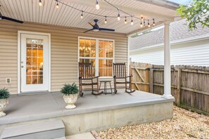 A covered patio with a ceiling fan, string lights, a wooden fence, and a seating area with chairs and a table. - New! 3BR/2BA House - 0.8 Mi From Downtown Auburn (Auburn)