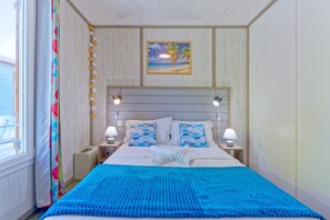 A hotel room with a bed, two bedside lamps, a painting above the bed, and a window with curtains. - Ô ti Zagaya - Clim - Piscines et plage (Le Vauclin)