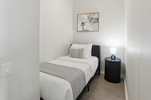 A bedroom with a bed, a bedside table, and a wall-mounted abstract painting. - City View Condo, Walk to Eaton Centre, Sleeps 6! | Parking Available (Toronto)