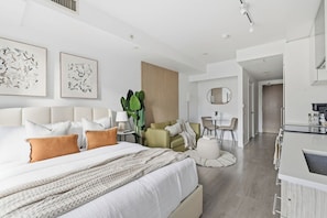 A modern hotel room with a large bed, a desk, and a dining area. - Stylish Studio, Steps to Yonge-Dundas Square | Parking Available (Toronto)