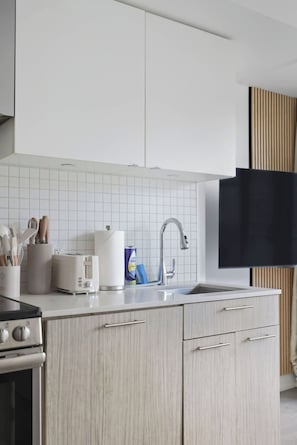 A modern kitchen with a built-in oven, a toaster, and a sink with a faucet. - Stylish Studio, Steps to Yonge-Dundas Square | Parking Available (Toronto)
