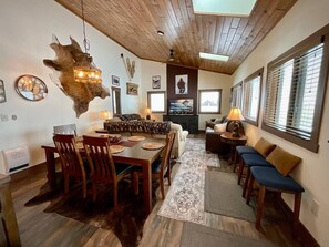 A spacious living area with a wooden ceiling, a dining table with chairs, a sofa, and a television. - New Listing! 3BR Luxury Big Sky | Mountain Retreat (Big Sky)