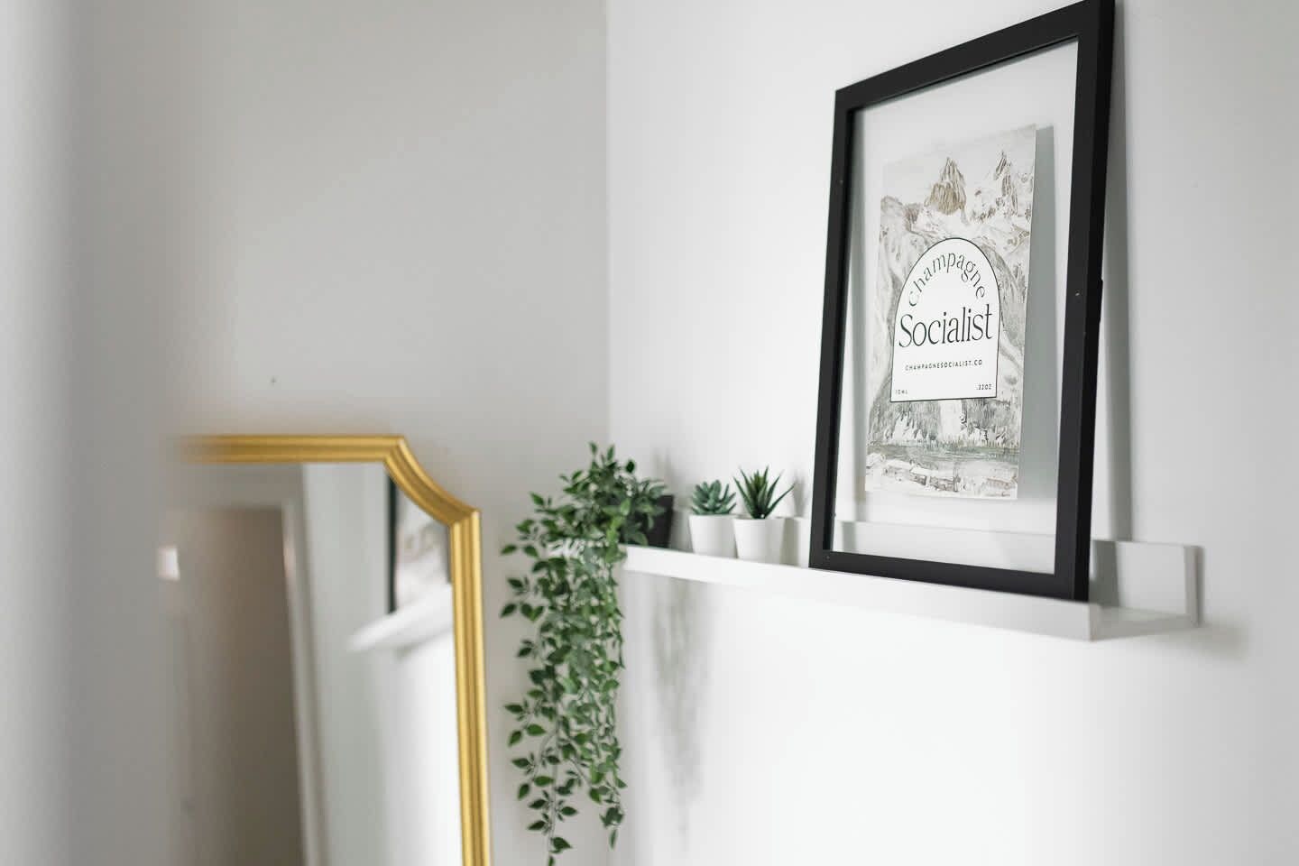 Ein gerahmtes Bild eines Kunstwerks mit sozialistischem Thema an einer Wand, eine mit goldener Rahmung versehene Treppe und ein Blumentopf.