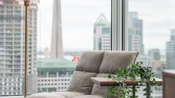 A modern chair with a cushioned seat and backrest, positioned next to a window with a view of a city skyline and a tower.
