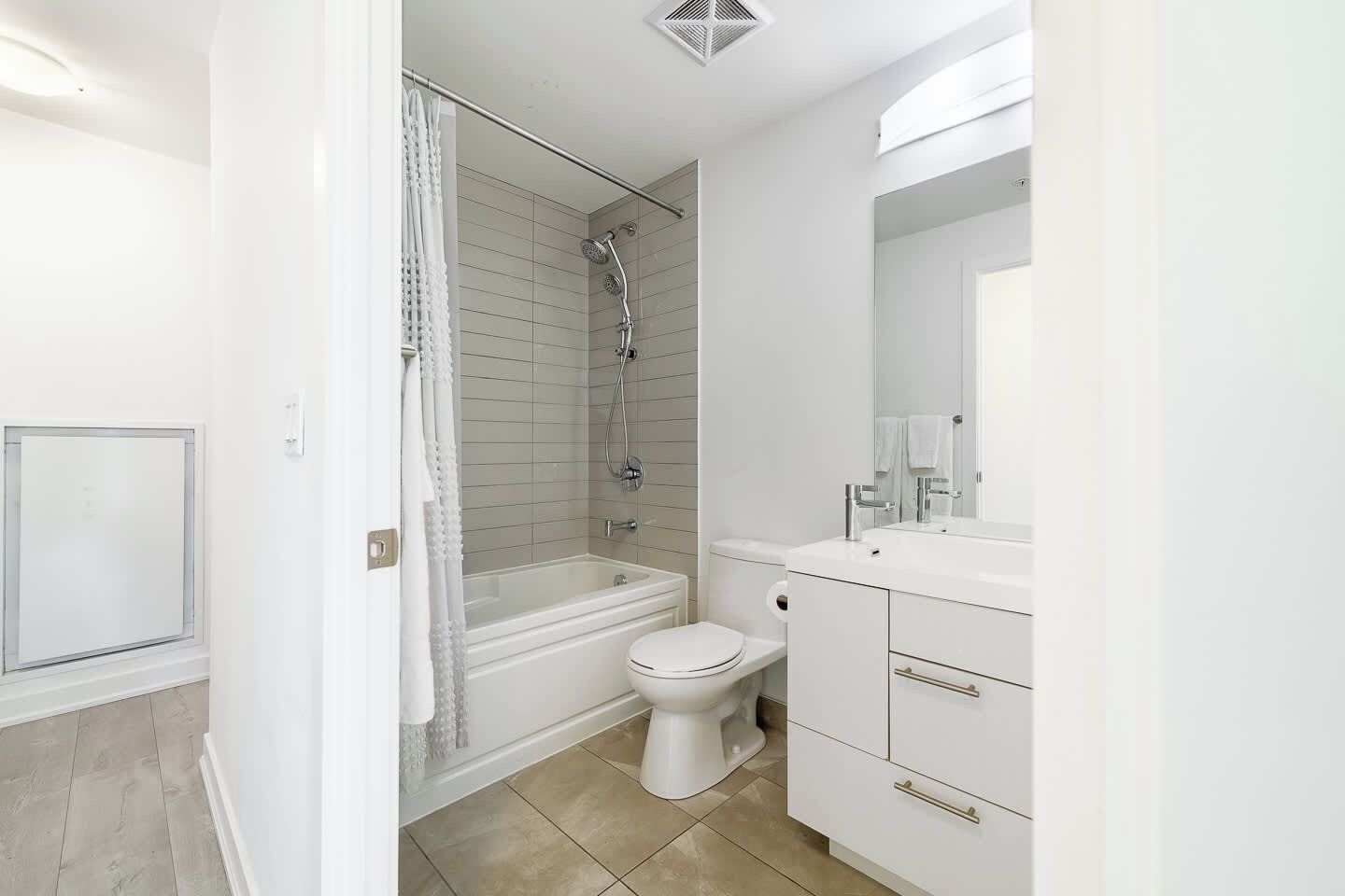 A modern bathroom with a shower, toilet, and vanity.