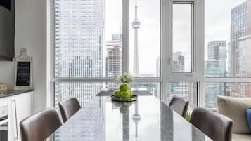 A modern dining area with a large window, a marble table, and a view of a cityscape including a tower.