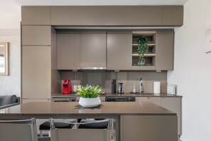A modern kitchen with built-in appliances, a central island with seating, and a potted plant. - Modern Cozy Condo in the Heart of Toronto! | Parking Available (Toronto)