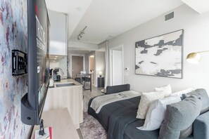 A modern hotel room with a bed, a desk, and a kitchenette. - City View Condo, Walk to Eaton Centre, Sleeps 6! | Parking Available (Toronto)