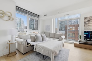 A modern living room with a sofa, a coffee table, and a TV. - CN Tower View 2BR/2BA | Free Parking Included | Parking Available (Toronto)
