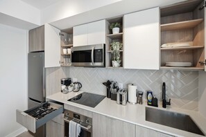 A modern kitchen with a built-in microwave, a coffee maker, and a toaster. - Sleek 2BR Condo, Balcony & Skyline Views | Parking (Toronto)