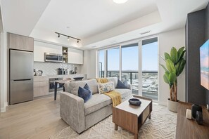 Eine moderne Wohnung mit Küche, Wohnbereich und großen Fenstern mit Blick auf die Stadt.