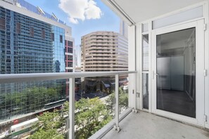 A balcony with a view of a cityscape, including modern buildings and a street with a train. - CN Tower Views Bright Modern 2BR | Parking Available (Toronto)