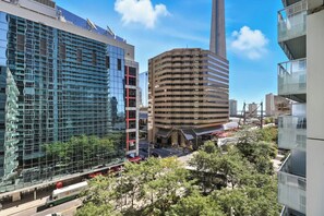 A modern urban area with high-rise buildings, including a distinctive cylindrical structure and a building with a reflective glass facade. - CN Tower Views Bright Modern 2BR | Parking Available (Toronto)