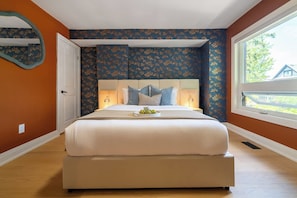 A bedroom with a large bed, a nightstand, a lamp, and a window with a view of a house. - Designer Trinity Bellwoods Gem Sleeps 12 Arcade | Parking Available (Toronto)
