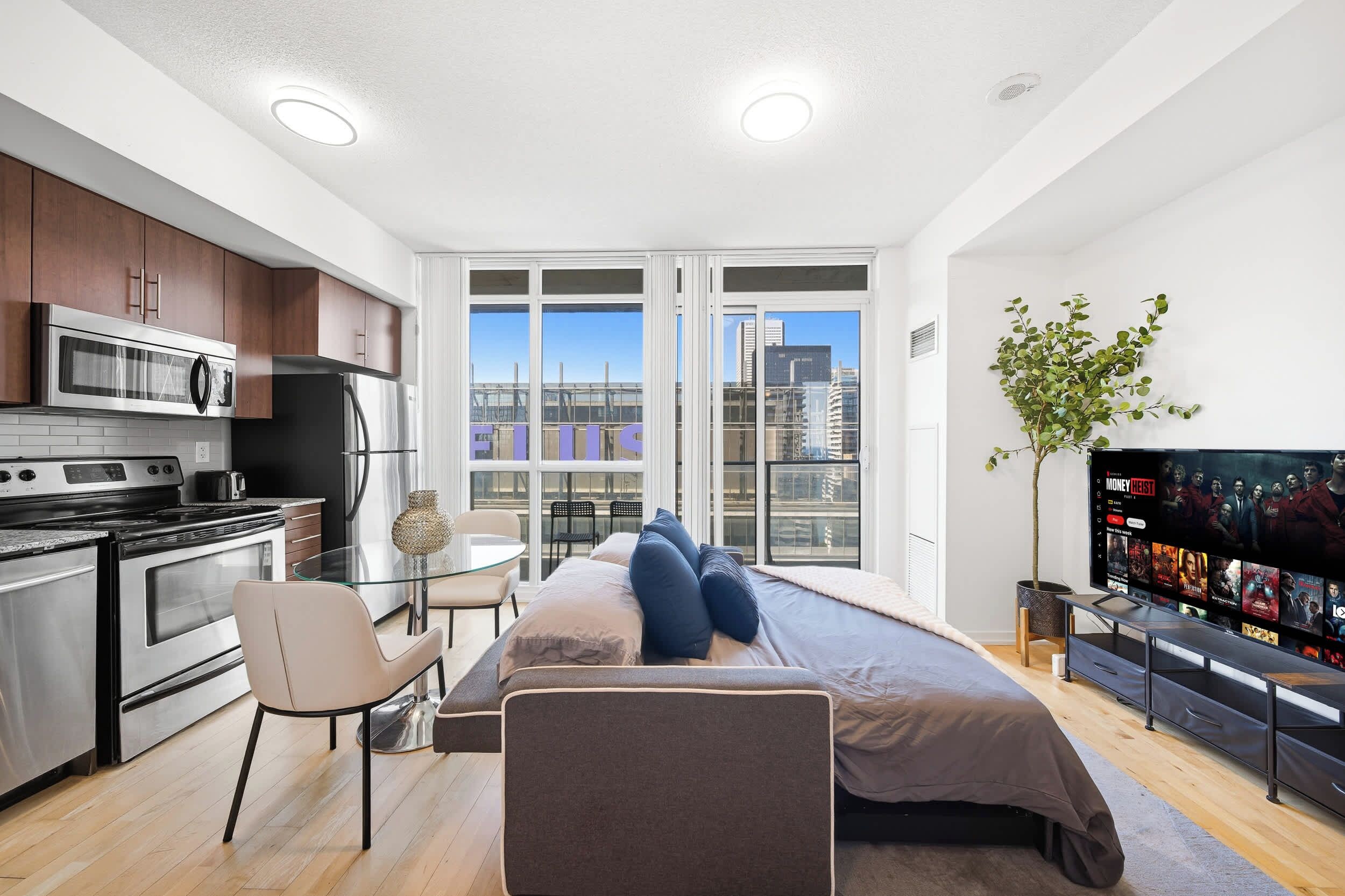 A modern apartment with a kitchen, dining area, and a bed with a TV.