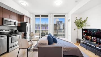 A modern apartment with a kitchen, dining area, and a bed with a TV.
