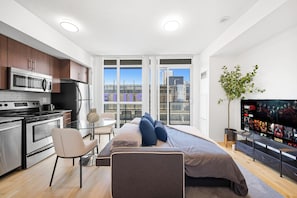 Un apartamento moderno con cocina, comedor y cama con televisor.