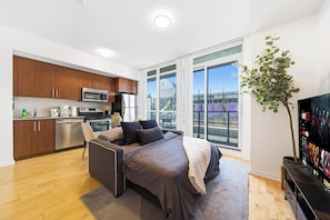Un apartamento moderno con kitchenette, una cama con vistas y un televisor sobre un mueble.